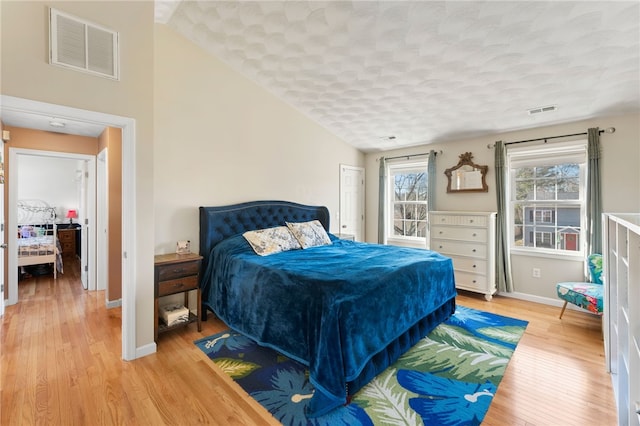 bedroom with light wood finished floors, visible vents, and baseboards