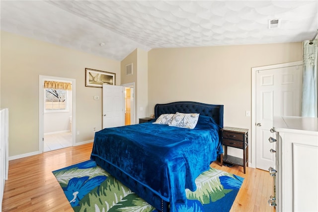 bedroom with vaulted ceiling, light wood-style floors, visible vents, and baseboards