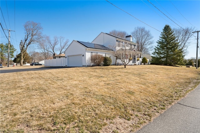 view of front of property with a front lawn, a garage, and roof mounted solar panels