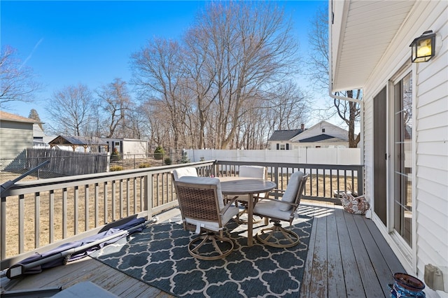 wooden terrace featuring outdoor dining area, a residential view, and a fenced backyard