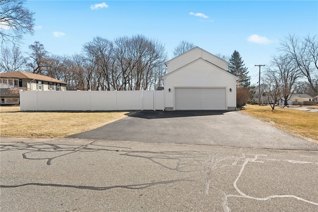 garage with aphalt driveway and fence