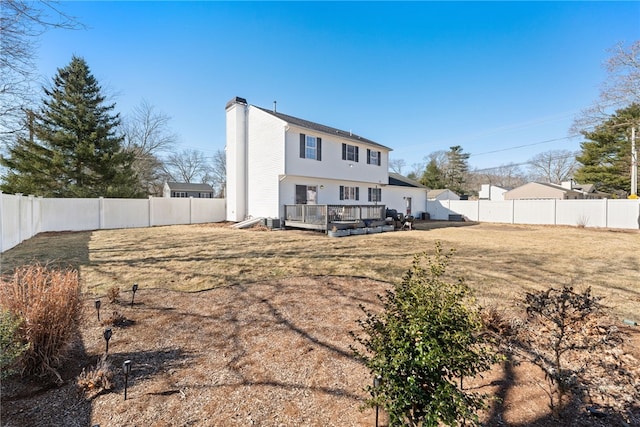 back of property with a fenced backyard, a yard, a wooden deck, central AC unit, and a chimney