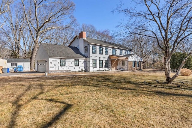 back of property featuring a yard, a chimney, and an attached garage