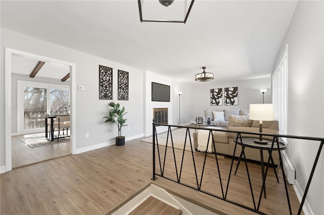 interior space featuring baseboards, beam ceiling, and wood finished floors