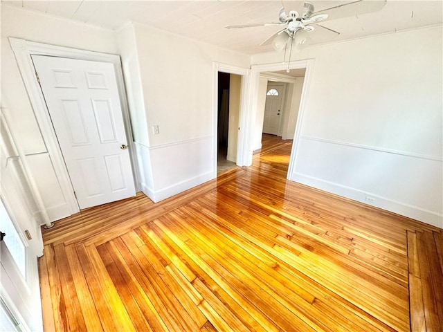 unfurnished room featuring light wood finished floors, baseboards, and a ceiling fan