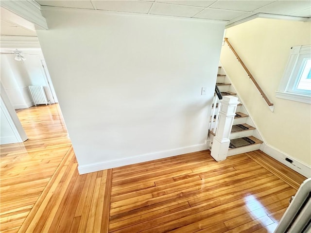 staircase with baseboards, hardwood / wood-style floors, and radiator heating unit