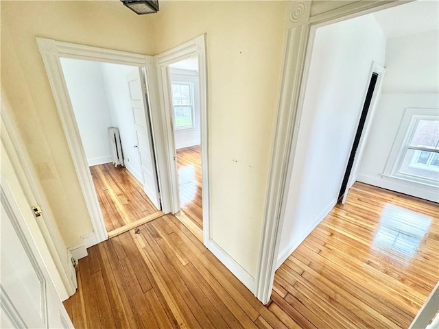 corridor featuring light wood-style flooring and baseboards