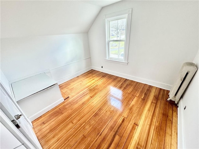 additional living space with light wood finished floors, vaulted ceiling, and baseboards