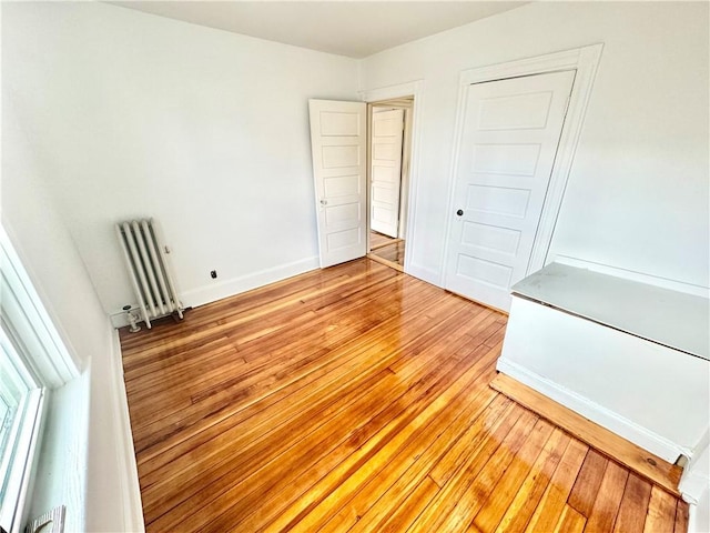 unfurnished bedroom featuring light wood-style flooring and radiator