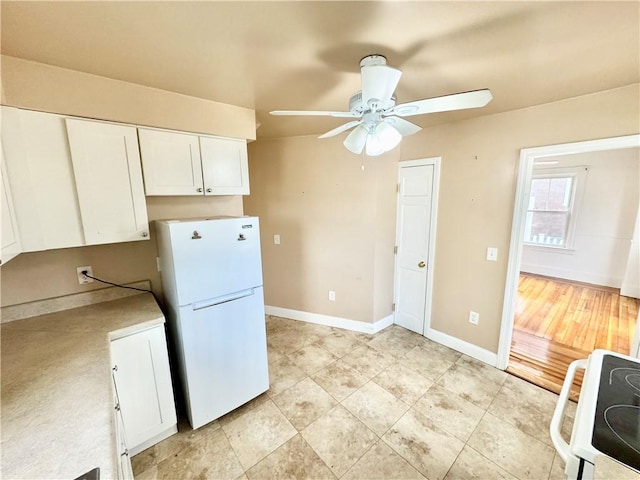 kitchen with white appliances, light tile patterned flooring, ceiling fan, white cabinets, and baseboards