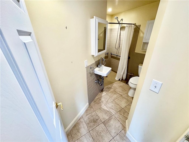 bathroom featuring a sink, toilet, tile patterned flooring, a shower with shower curtain, and baseboards