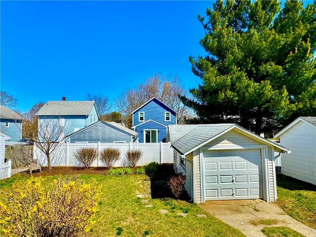 view of front of home featuring a garage, fence, a front lawn, an outbuilding, and driveway