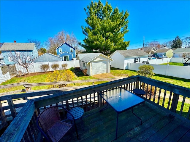 wooden deck with a residential view, a garage, an outbuilding, a fenced backyard, and a lawn