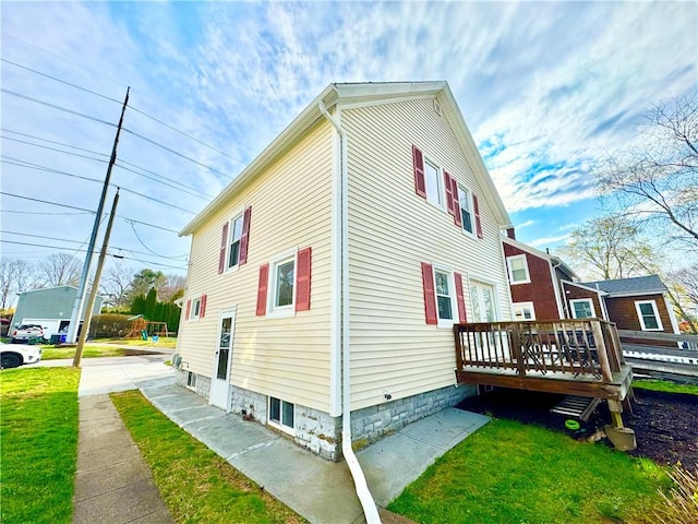 view of side of property featuring a yard and a wooden deck