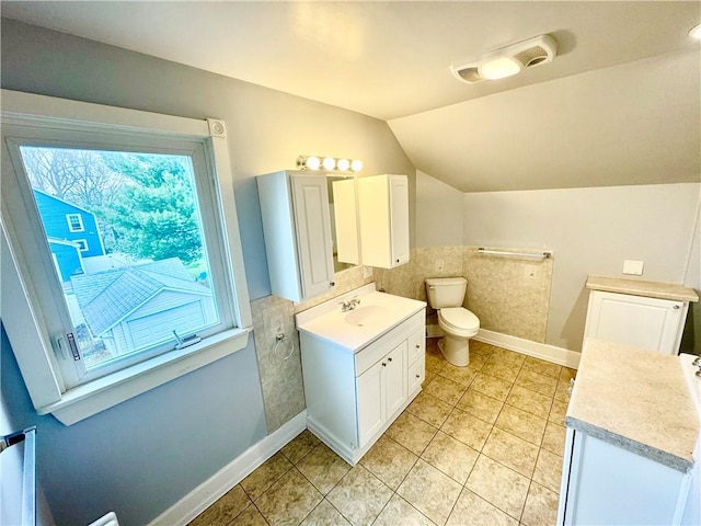 bathroom featuring toilet, baseboards, lofted ceiling, tile patterned flooring, and vanity