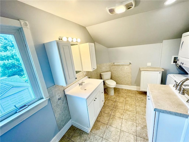 bathroom with toilet, tile patterned floors, baseboards, vaulted ceiling, and vanity