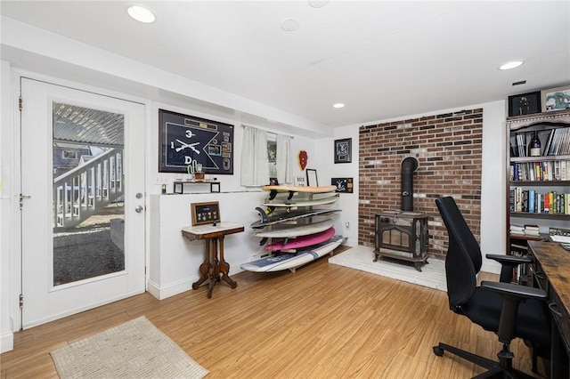 home office with recessed lighting, baseboards, wood finished floors, and a wood stove