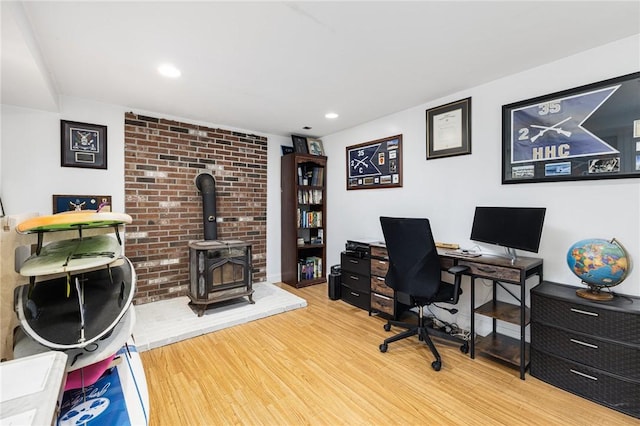 office space with recessed lighting, a wood stove, and light wood-style floors