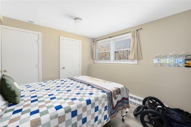 bedroom with baseboard heating and wood finished floors