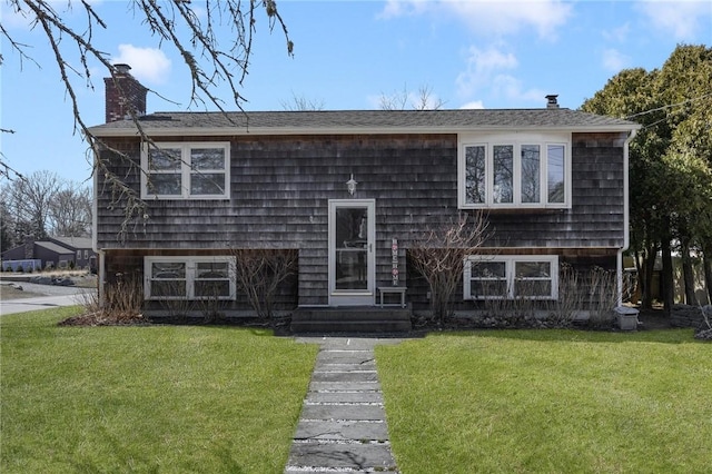 split foyer home featuring a chimney, a shingled roof, a front yard, and entry steps