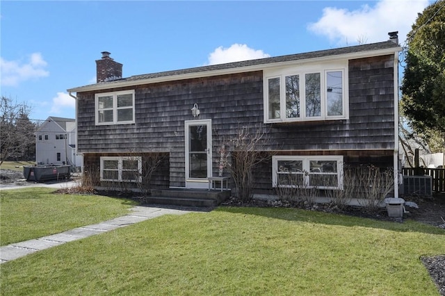 view of front of property with entry steps, a front yard, and a chimney