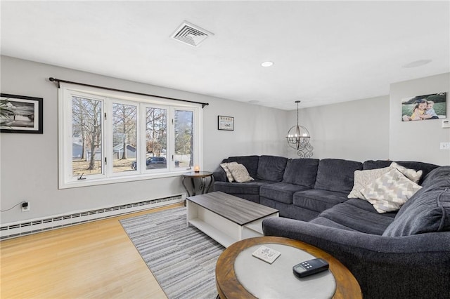 living area with visible vents, an inviting chandelier, wood finished floors, and a baseboard radiator