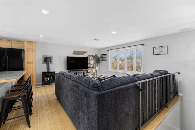 living area with visible vents, recessed lighting, a wood stove, and light wood-style floors