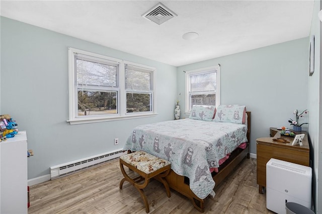 bedroom with visible vents, a baseboard heating unit, baseboards, and wood finished floors