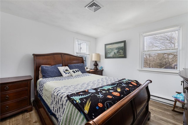 bedroom featuring visible vents, wood finished floors, and a baseboard radiator