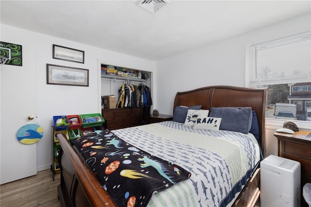 bedroom featuring a closet, visible vents, and wood finished floors