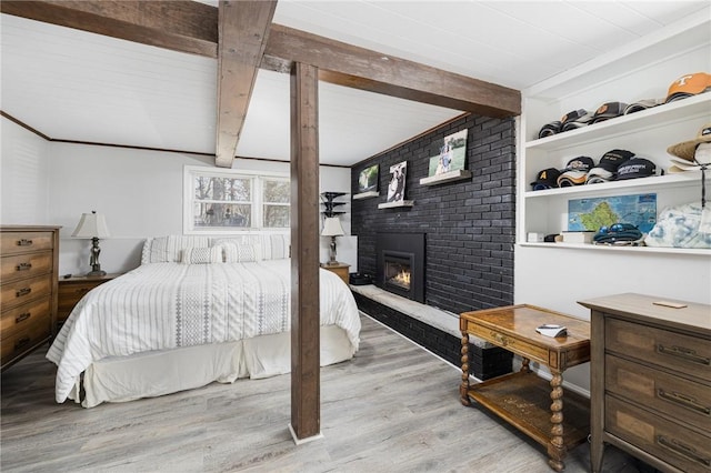 bedroom featuring a fireplace, lofted ceiling with beams, and wood finished floors