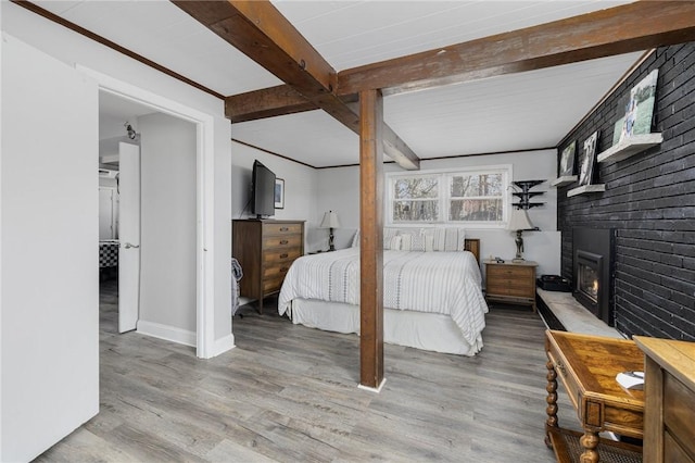 bedroom with a fireplace, beam ceiling, wood finished floors, and baseboards