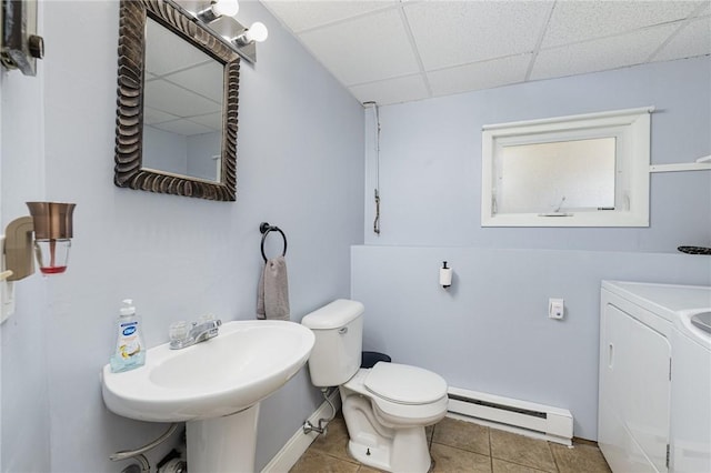 bathroom with a baseboard radiator, separate washer and dryer, a drop ceiling, tile patterned flooring, and toilet