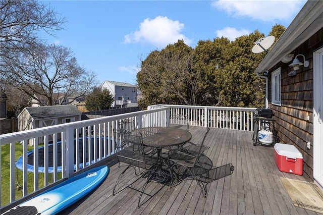 deck with a storage unit, an outbuilding, a fenced backyard, a residential view, and outdoor dining area