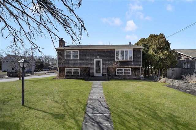 raised ranch with a chimney and a front yard