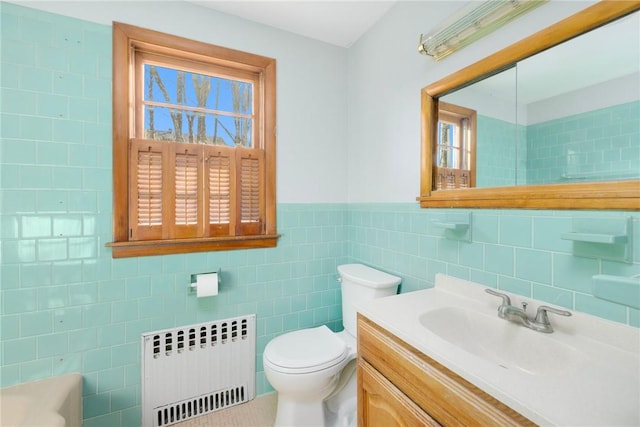 bathroom featuring vanity, a wainscoted wall, radiator heating unit, tile walls, and toilet