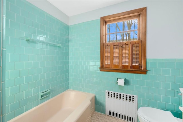 bathroom featuring radiator, a tub, tile patterned flooring, tile walls, and toilet