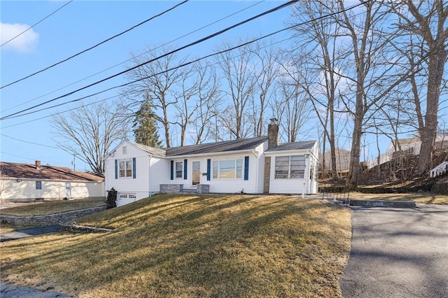 view of front of property featuring a front yard, a garage, and a chimney