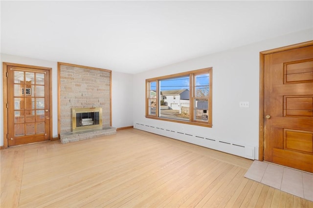 unfurnished living room with a stone fireplace, wood finished floors, and a baseboard radiator