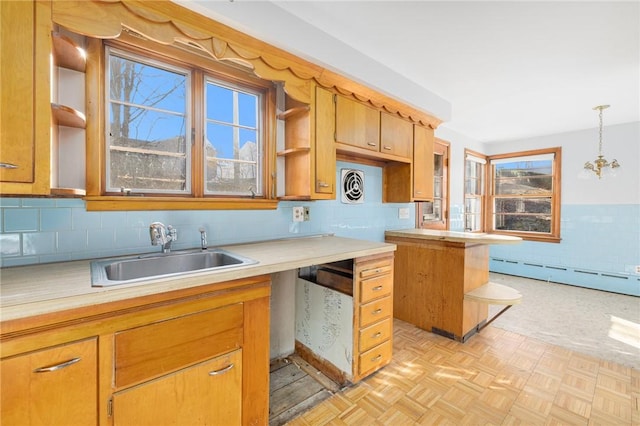 kitchen featuring a sink, decorative backsplash, baseboard heating, and light countertops