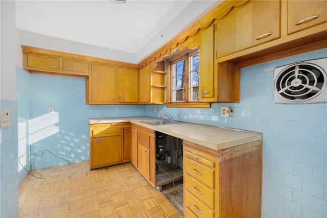 kitchen with brown cabinetry, open shelves, a sink, light countertops, and tile walls