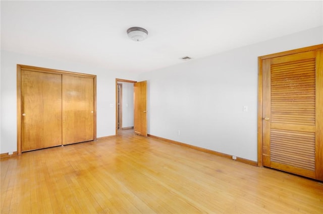 unfurnished bedroom with visible vents, baseboards, and light wood-style floors