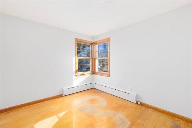 unfurnished room with baseboard heating, baseboards, and wood-type flooring