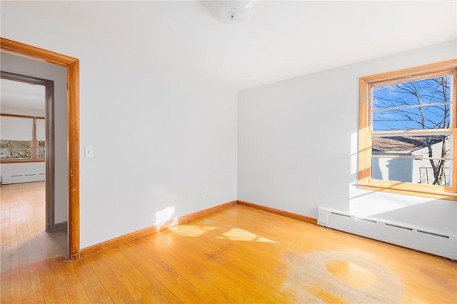 empty room featuring baseboards, wood-type flooring, and a baseboard heating unit