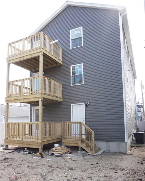 back of property featuring central AC unit, entry steps, and a balcony