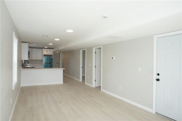 unfurnished living room with recessed lighting, baseboards, and light wood-style floors