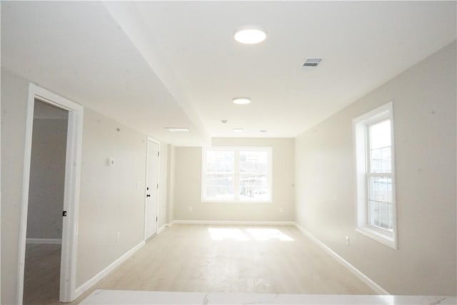 spare room featuring baseboards, a wealth of natural light, and light wood-type flooring