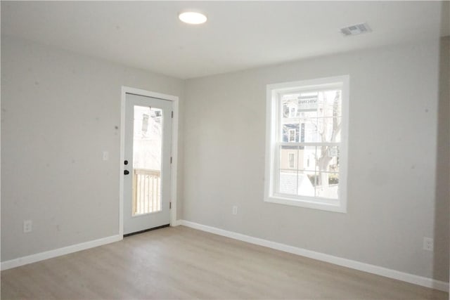 foyer entrance with a wealth of natural light, light wood finished floors, and baseboards