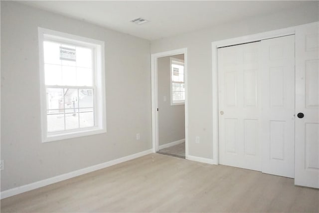 unfurnished bedroom with light wood-style flooring, baseboards, visible vents, and a closet