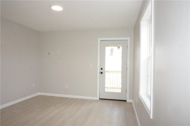 spare room featuring light wood-style floors and baseboards